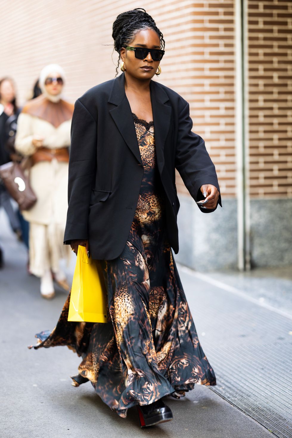A guest is seen wearing a print tiger dress and black blazer outside the Fendi show during Milan Fashion Week