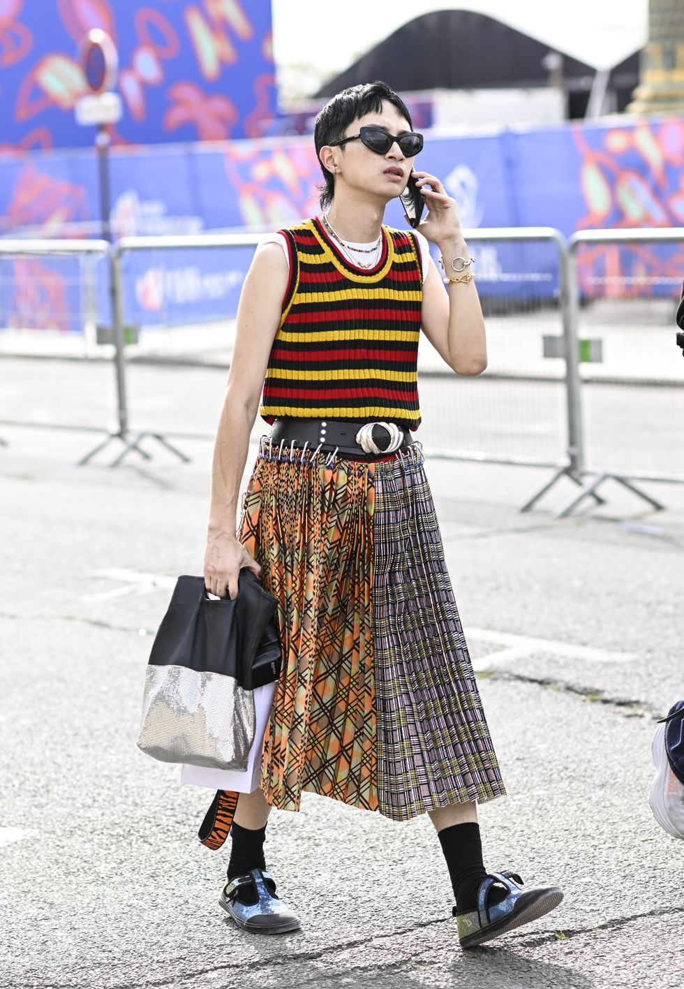 A guest is seen wearing a red and yellow stripe vest, plaid skirt, black and white bag and blue shoes outside the Dior show during the Womenswear Spring/Summer 2024 as part of Paris Fashion Week
