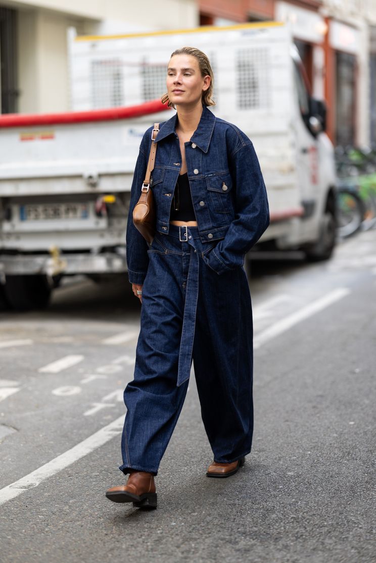 Julie Pelipas wears black jacket, wide leg denim jeans outside