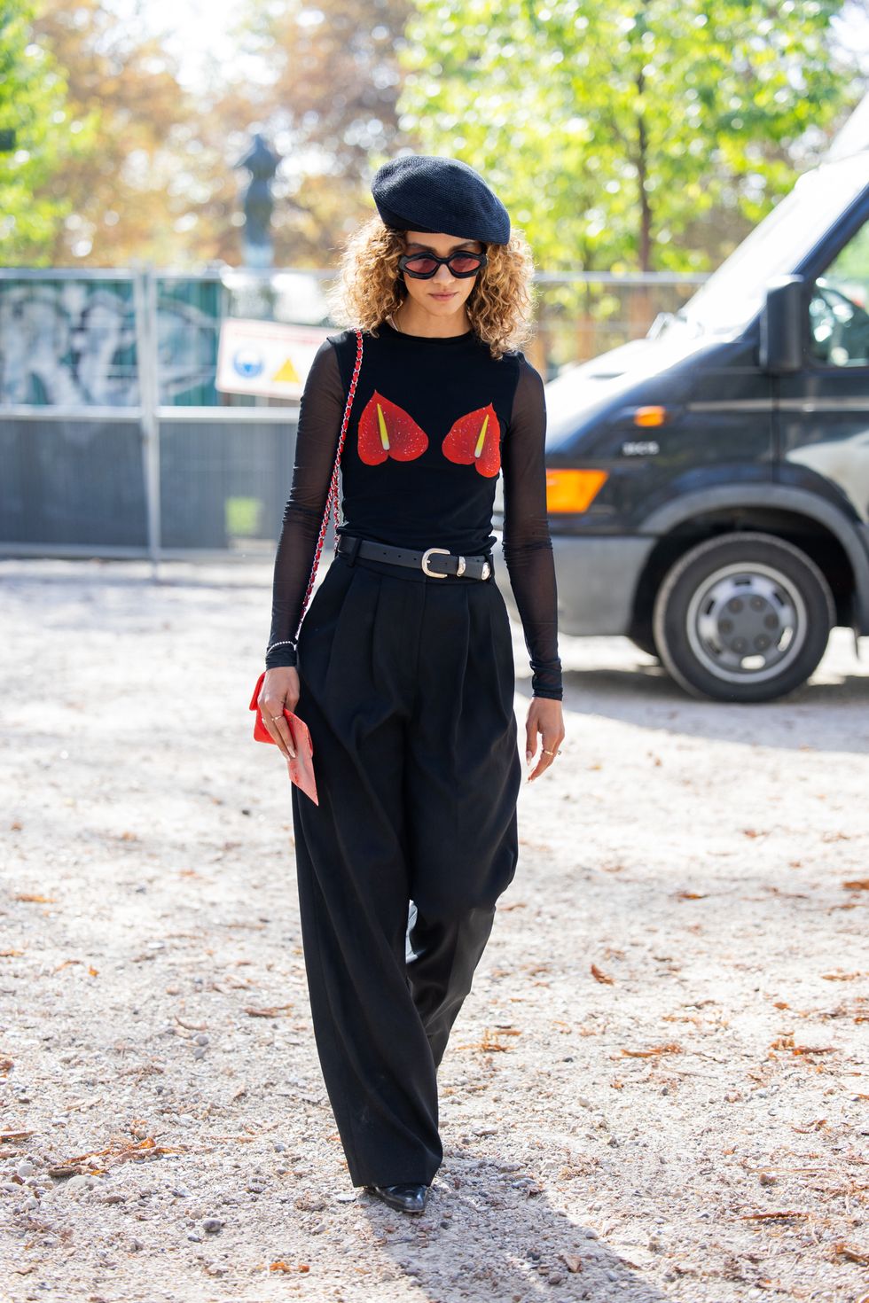 A guest wears black beret, black transparent top, wide leg pants outside Akris during the Womenswear Spring/Summer 2024 as part of Paris Fashion Week