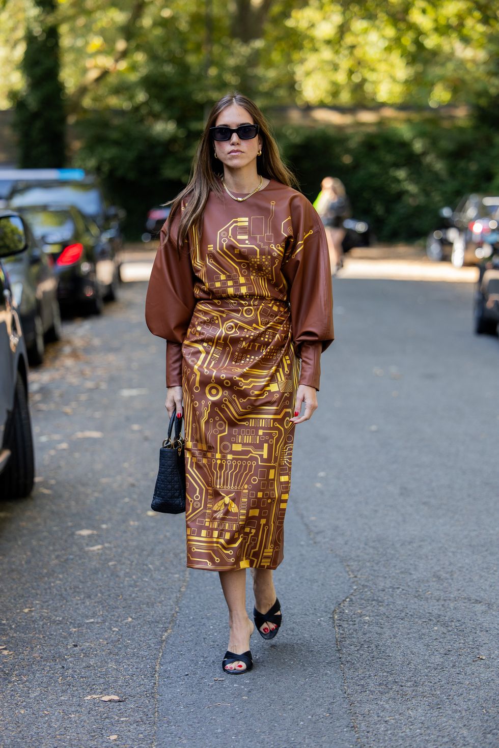 A guest wears brown dress with yellow graphic print, Dior bag outside Bora Aksu during London Fashion Week September