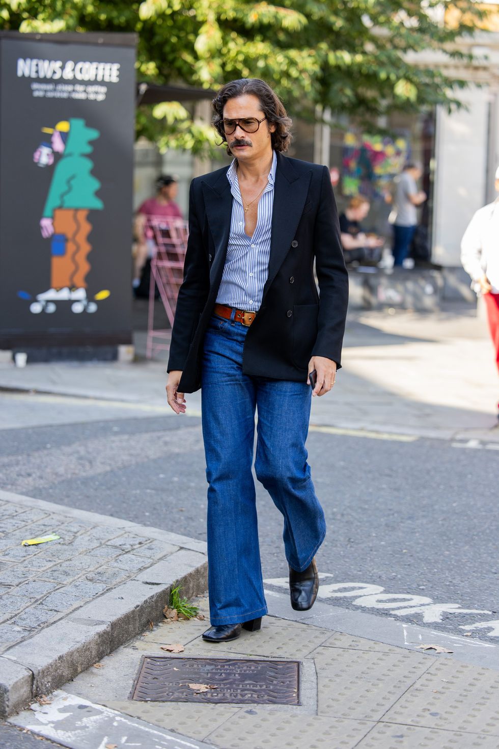 A guest wears denim jeans, black blazer outside JW Anderson during London Fashion Week September