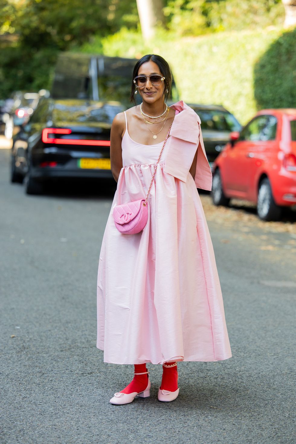A guest wears pink dress, Chanel bag, red tights, shoes, necklace outside Bora Aksu during London Fashion Week September