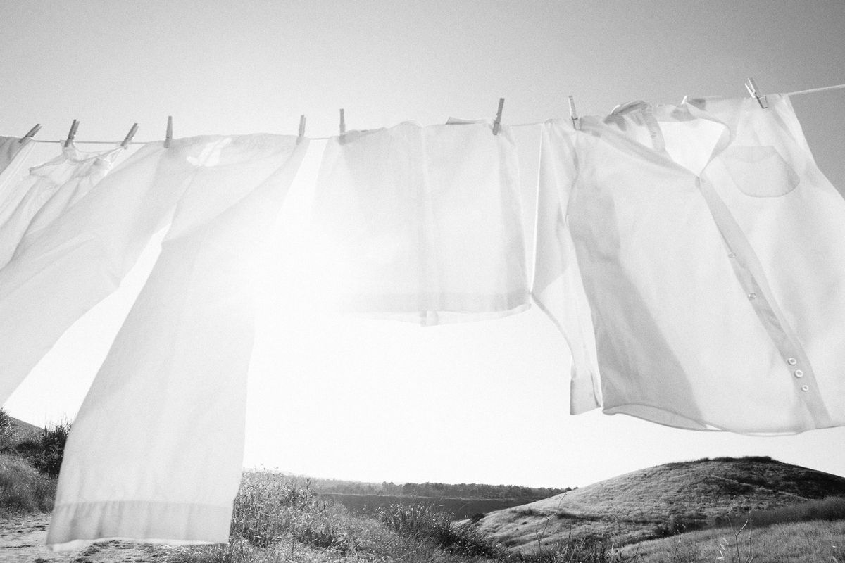 Clothesline of white cotton pants and button-down shirts, blowing the in breeze.