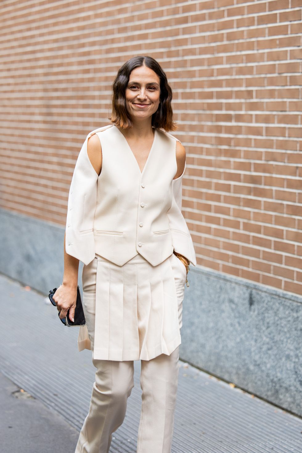 Erika Boldrin wears creme white cut out vest with long sleeves, skirt with fringes, pants outside Fendi during the Milan Fashion Week
