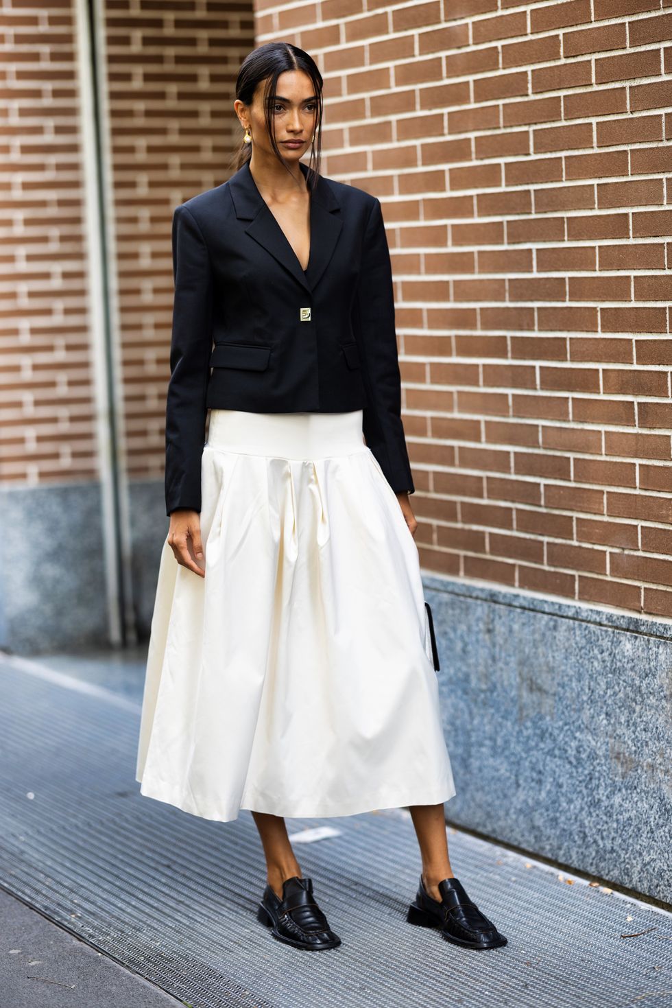Kelly Gale is seen wearing a white wide skirt and short black blazer outside Fendi show during the Milan Fashion Week